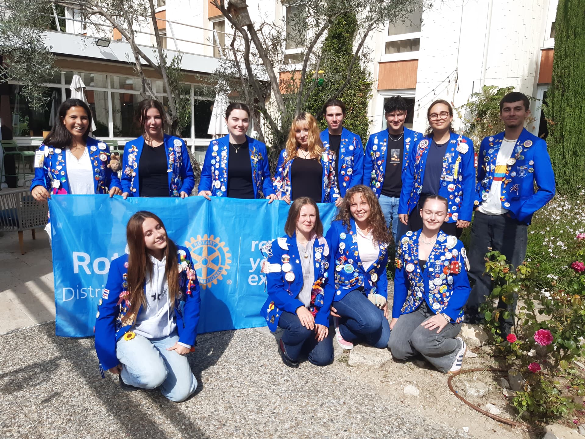 Rotex du district 1760 en blazers bleus couverts de pin's, réunis derrière la bannière Rotary Youth Exchange