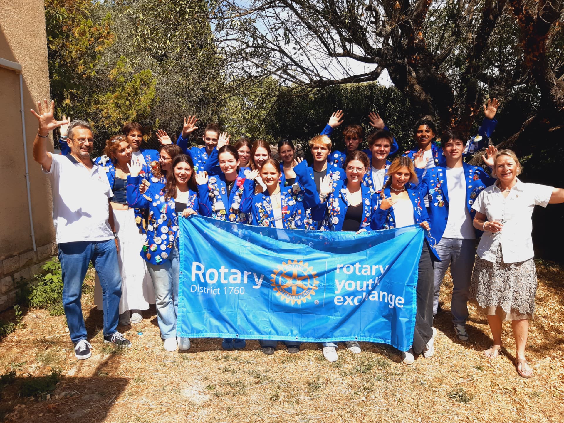 Groupe de Rotex et bénévoles du pôle jeunesse saluant derrière la bannière Rotary District 1760
